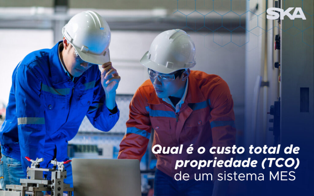 dois operadores industriais analisando custo total de propriedade no notebook da empresa